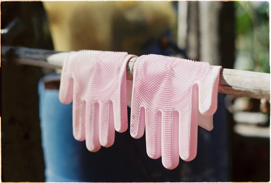 Vue de côté d’une jeune femme concentrée, portant des gants en latex, en train de nettoyer un miroir dans une pièce lumineuse en journée